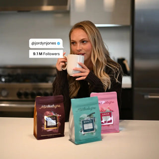 Jordyn Jones Drinking coffee in a kitchen table, with three coffee bags 