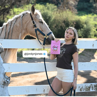 Jordyn Jones holding a pink bag next to a horse in an outdoor setting