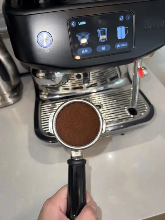 Customer photo: a portafilter of freshly ground coffee at an espresso machine